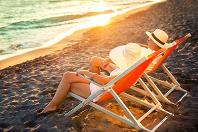 Taking a vacation. Couple relaxing on beach during sunset.